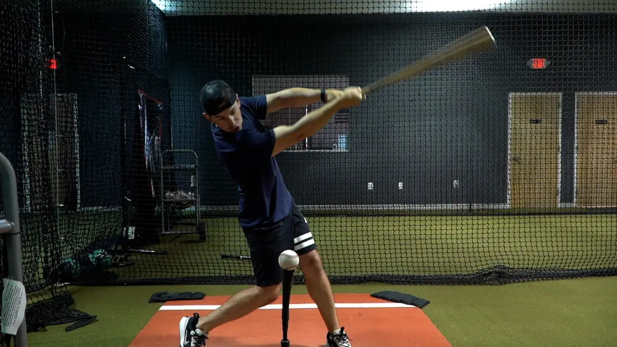 Chris Winters finishing a swing off a tee in the cage